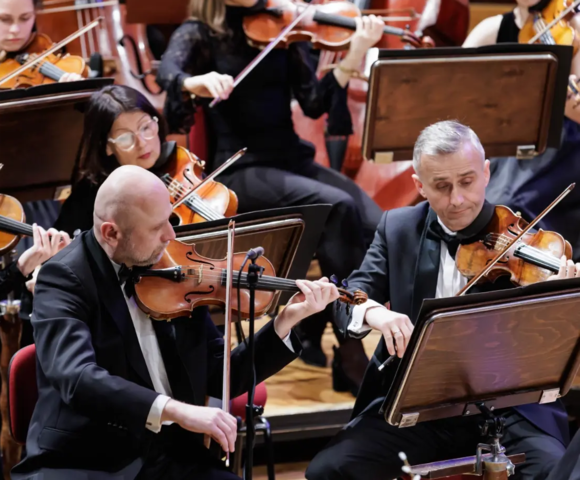 Musicians of Sinfonietta Cracovia performing on stage during a concert, playing string instruments.