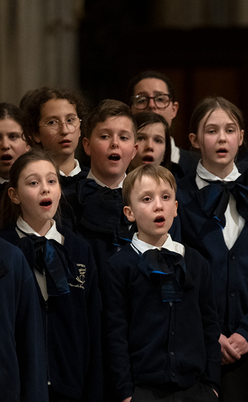 Chór dziecięcy w granatowych strojach śpiewa podczas koncertu Credo w Bazylice Santa Maria Maggiore w Rzymie.