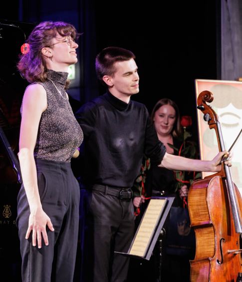 Pianist and cellist standing together on stage after their performance.