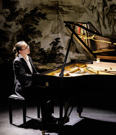 Pianist performing at an open Steinway & Sons concert grand piano in a historic interior.