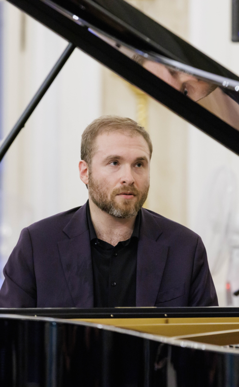 Pianista siedzący przy fortepianie podczas koncertu.